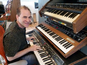 Mitch Sigman, Lead Designer At Cherry Audio, With Vintage Synths including PolyMoog, Prophet 5, and Roland Jupiter 4.